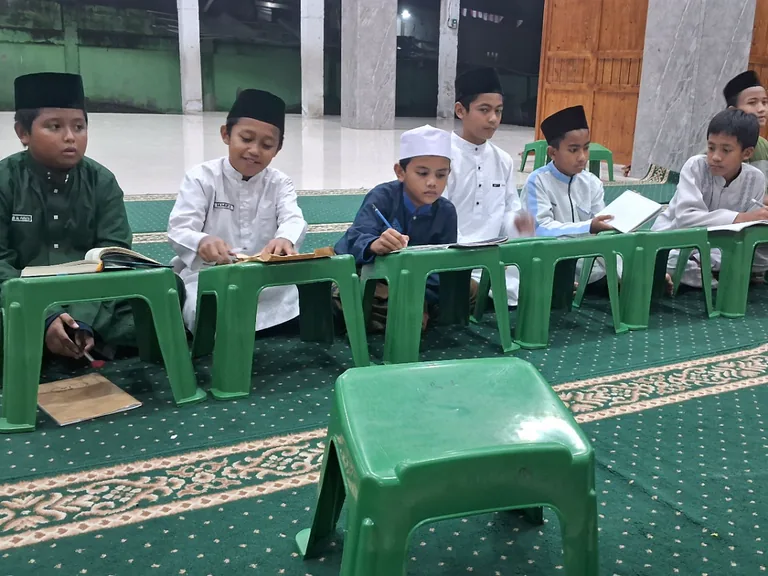 Santri belajar bersama dengan buku terbuka di meja masing-masing.